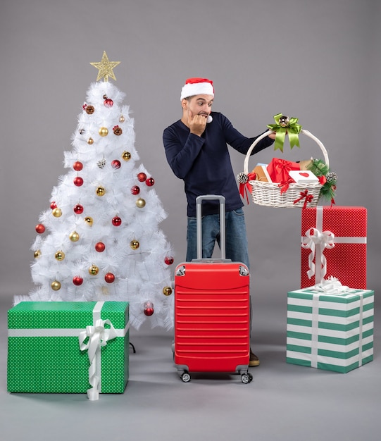 Vooraanzicht jonge man opgewonden opening geschenkmand op grijs geïsoleerd