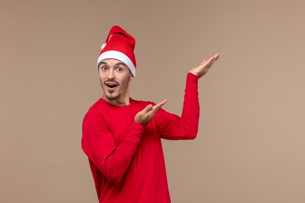 Vooraanzicht jonge man poseren met verbaasd gezicht op bruine achtergrond emotie vakantie kerst