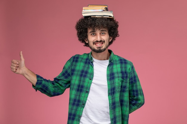 Vooraanzicht jonge man poseren terwijl boeken op zijn hoofd zijn