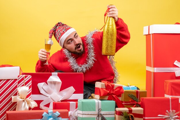 Vooraanzicht jonge man rondhangen presenteert vieren met champagne op gele achtergrond