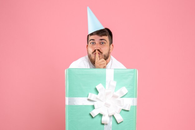 Vooraanzicht jonge man staande in huidige doos op de roze foto kleur emotie xmas pyjama party