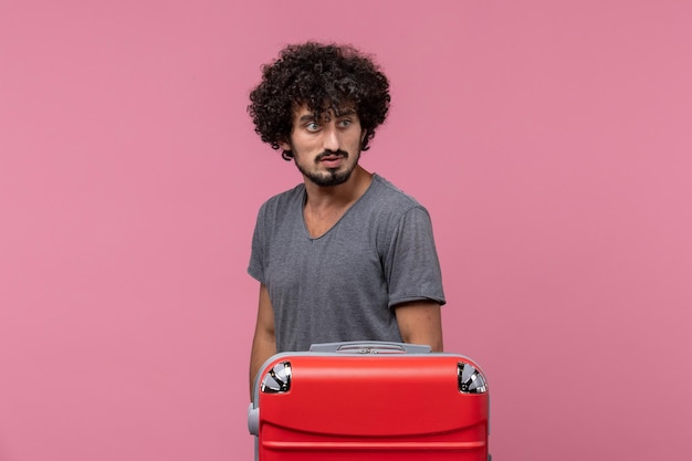 Vooraanzicht jonge man staat gewoon en bereidt zich voor op een reis op roze ruimte