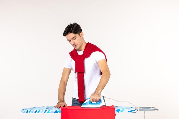 Vooraanzicht jonge man strijken handdoek op een witte achtergrond schoon huishoudelijk werk thuiswerk emotie mode kleding man