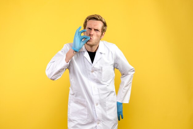 Vooraanzicht jonge mannelijke arts op gele achtergrond medic covid pandemie