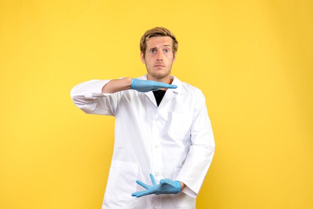 Gratis foto vooraanzicht jonge mannelijke arts op gele achtergrond menselijke medic covid pandemie