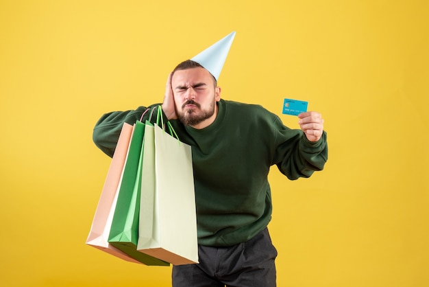 Vooraanzicht jonge mannelijke bankkaart en winkelpakketten op gele achtergrond