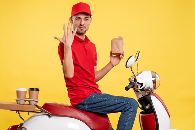 Vooraanzicht jonge mannelijke koerier in rood uniform op gele achtergrond