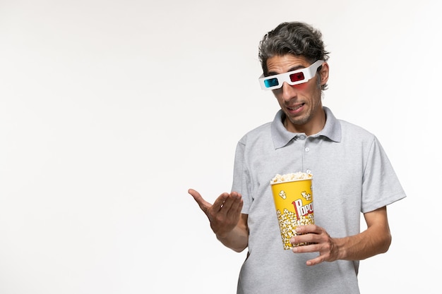 Vooraanzicht jonge mannelijke popcorn in d zonnebril op een wit bureau te houden