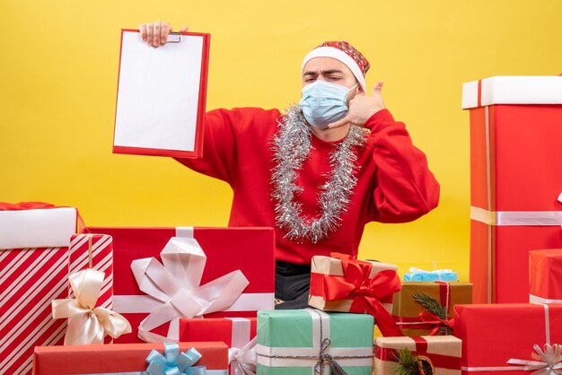 Vooraanzicht jonge mannelijke rondhangen presenteert in masker met opmerking over gele achtergrond