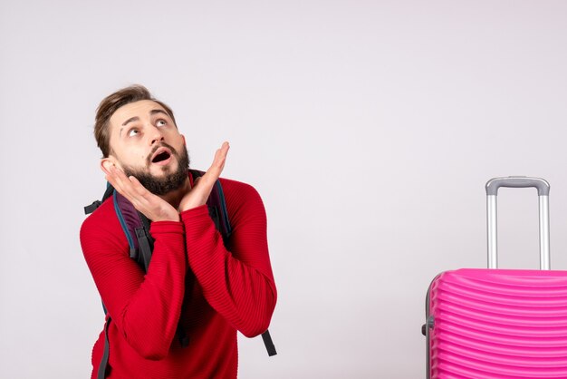 Vooraanzicht jonge mannelijke toerist met rugzak en roze tas op witte muur covid vliegtuig vakantie emotie virus vlucht kleur