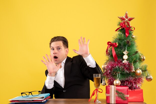 Vooraanzicht jonge mannelijke werknemer achter zijn tafel zitten