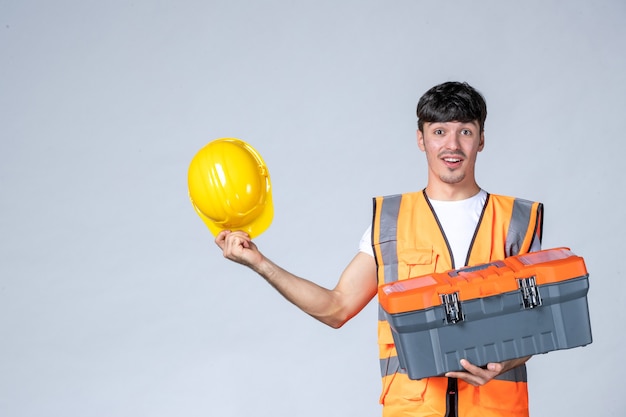 vooraanzicht jonge mannelijke werknemer met zware gereedschapskoffer op een witte achtergrond