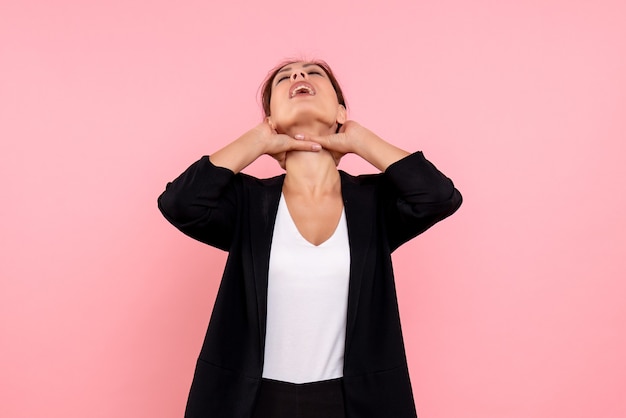 Vooraanzicht jonge mooie vrouw in een donkere jas op de roze achtergrond