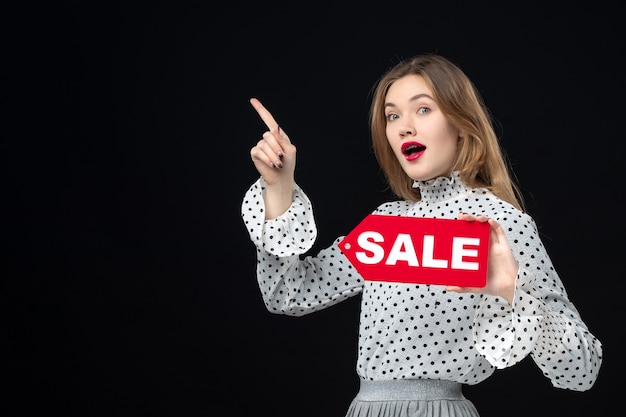 Vooraanzicht jonge mooie vrouw met verkoop schrijven op zwarte muur kleuren winkelen mode foto vrouw emotie rood