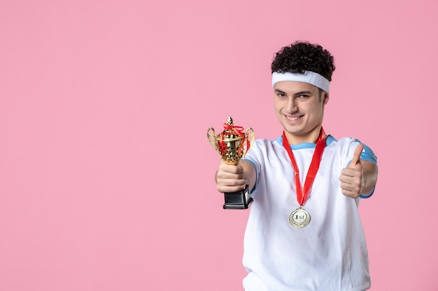 Gratis foto vooraanzicht jonge speler in sportkleren met gouden kop op roze muur