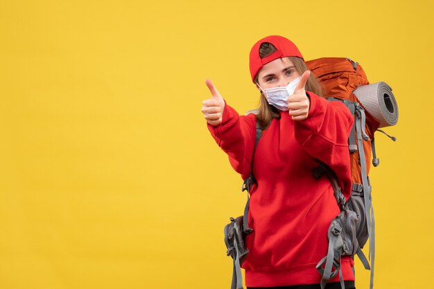 Vooraanzicht jonge toerist met toeristenrugzak en masker die duimen opgeeft