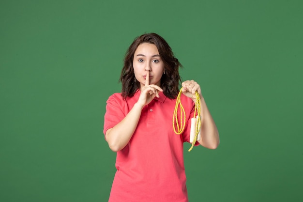 Vooraanzicht jonge verkoopster met springtouw op groene achtergrond verkoop boutique uniform winkelen werknemer sport gezondheid baan presenteert