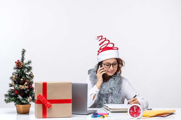 Vooraanzicht jonge vrouw aan het werk tijdens vakantiedagen praten aan de telefoon op wit bureau