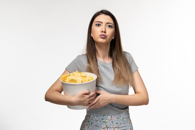 Vooraanzicht jonge vrouw chips eten kijken naar film op het licht witte oppervlak