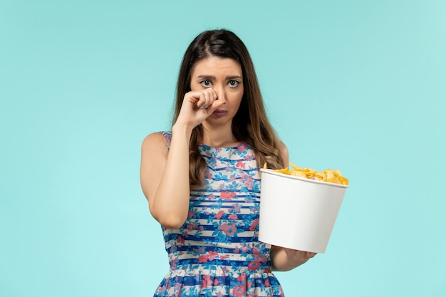 Vooraanzicht jonge vrouw cips eten en kijken naar film huilen op blauwe ondergrond