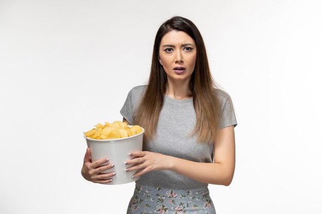 Vooraanzicht jonge vrouw cips eten en kijken naar film op licht wit oppervlak