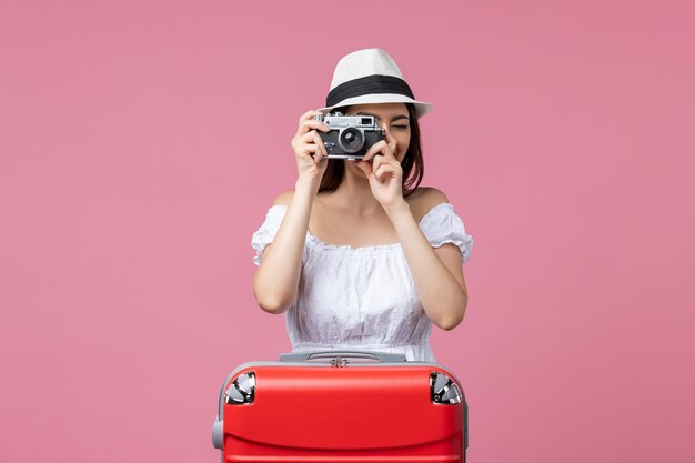 Vooraanzicht jonge vrouw die een foto neemt op vakantie op de roze muur zomer kleur vakantie reis warmte reis