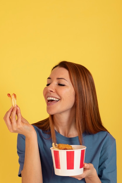 Gratis foto vooraanzicht jonge vrouw die frietjes eet