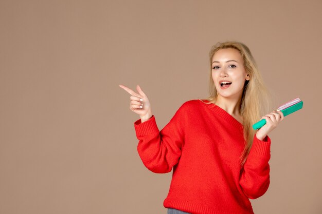 vooraanzicht jonge vrouw die haar haar op donkerbruine muur borstelt