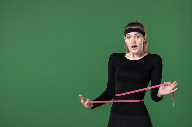 Vooraanzicht jonge vrouw die haar lichaam meet met centimeter op groene achtergrond zwarte atleet vrouw kleur gezondheid fit lichaamstraining