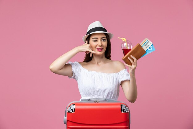 Vooraanzicht jonge vrouw die sap drinkt met kaartjes op vakantie op de roze muur zomerrust reis vrouw reis