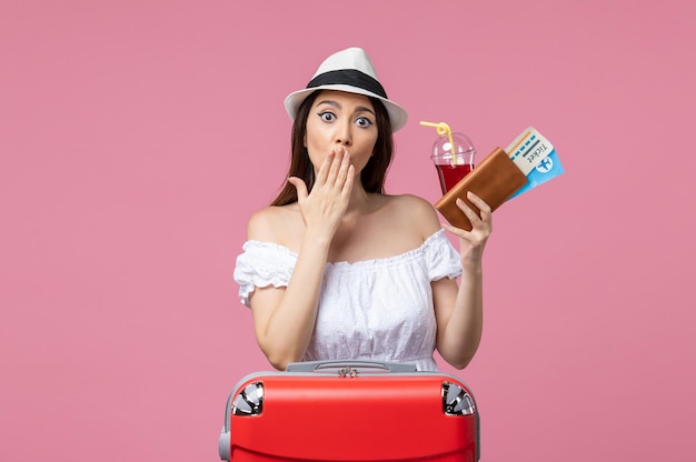 Vooraanzicht jonge vrouw die sap drinkt met kaartjes op vakantie op de roze muur zomerrust reis vrouw reis