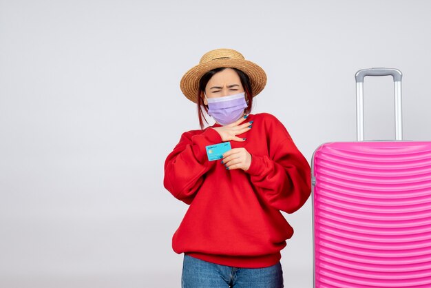 Vooraanzicht jonge vrouw die zich voorbereidt op een reis in masker op witte muur