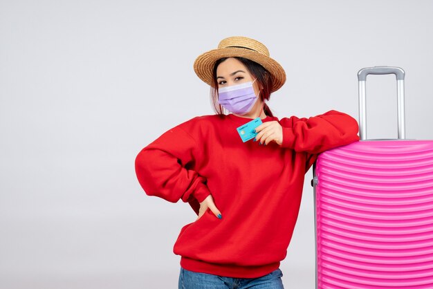 Vooraanzicht jonge vrouw die zich voorbereidt op een reis in masker op witte muur