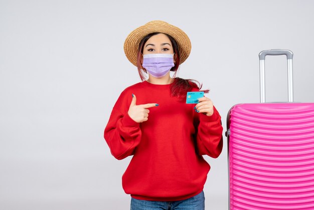 Vooraanzicht jonge vrouw die zich voorbereidt op een reis in masker op witte muur