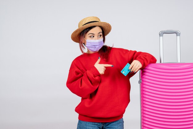 Vooraanzicht jonge vrouw die zich voorbereidt op een reis in masker op witte muur