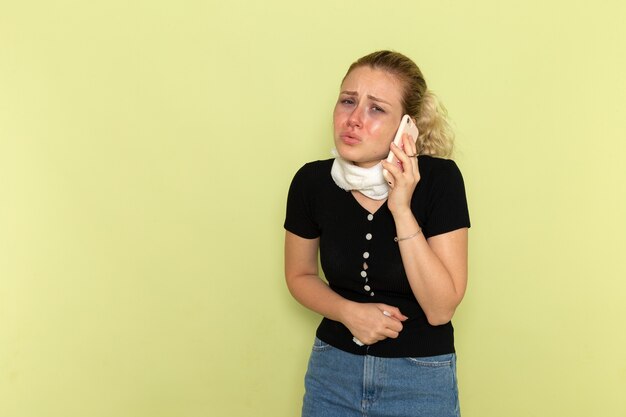 Vooraanzicht jonge vrouw erg ziek en ziek voelen praten aan de telefoon op de groene muur ziekte vrouwelijke geneeskunde ziekte