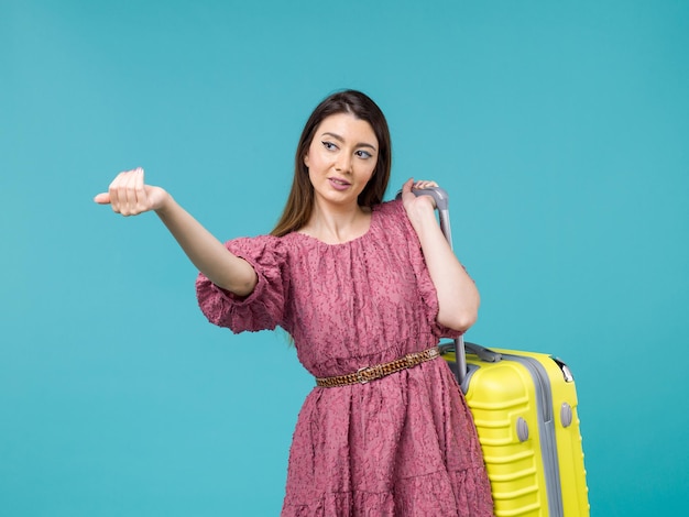 Vooraanzicht jonge vrouw gaat op vakantie met haar gele tas op lichtblauwe achtergrond reis zomer reis vrouw menselijke zee