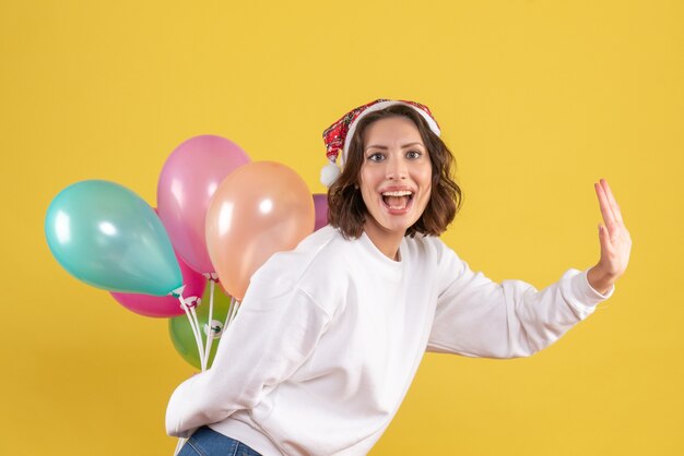 Vooraanzicht jonge vrouw gelukkig verbergt kleurrijke ballonnen Nieuwjaar kerst kleur vakantie vrouw emotie