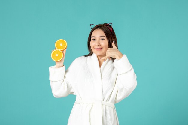 vooraanzicht jonge vrouw in badjas met gesneden sinaasappel op blauwe achtergrond