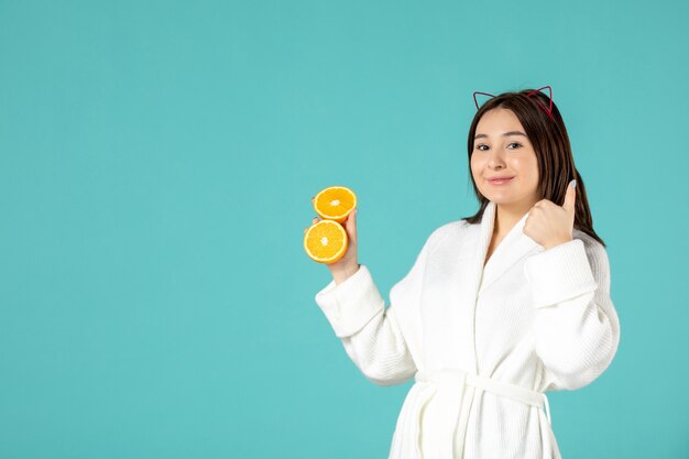 vooraanzicht jonge vrouw in badjas met gesneden sinaasappel op blauwe achtergrond