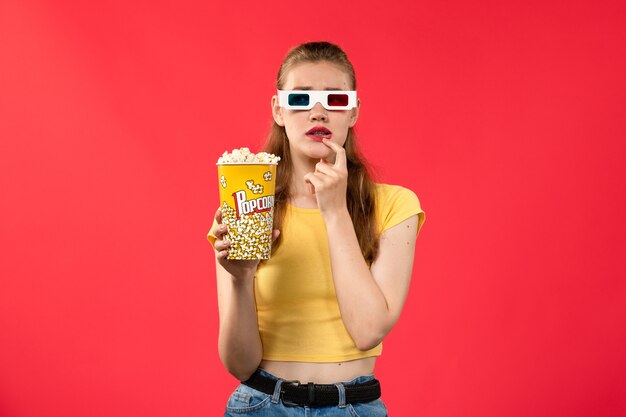 Vooraanzicht jonge vrouw in bioscoop houden popcorn met denken uitdrukking op rode muur films theater bioscoop snack vrouwelijke leuke film