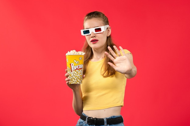 Vooraanzicht jonge vrouw in bioscoop houden popcorn pakket op de rode muur films theater bioscoop snack leuke film