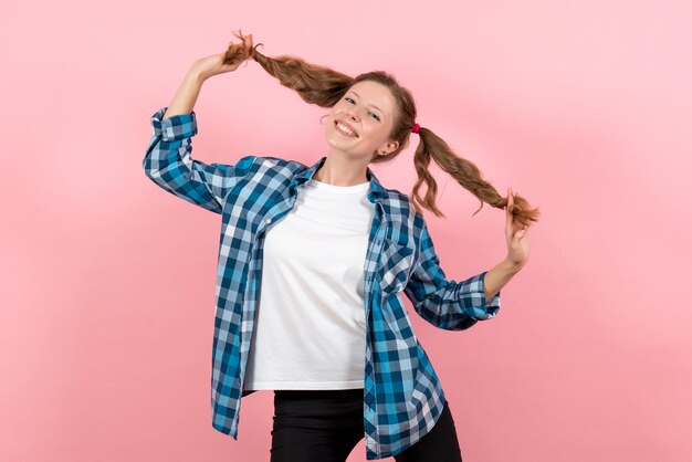 Vooraanzicht jonge vrouw in blauw geruit hemd poseren en lachend op roze muur vrouw emoties model mode meisjes kleur