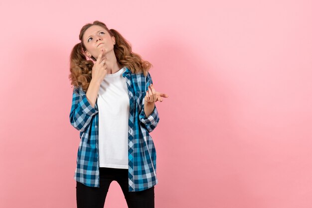 Vooraanzicht jonge vrouw in blauw geruit overhemd poseren denken op roze achtergrond jeugd emotie meisje model mode jongen