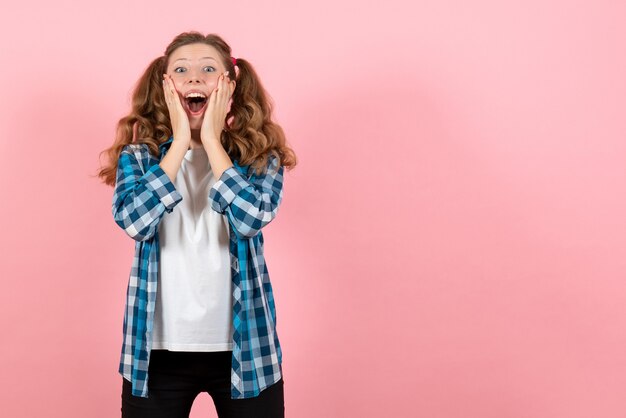 Vooraanzicht jonge vrouw in blauw geruit overhemd poseren op roze achtergrond kind jeugd emoties model mode vrouw kleur