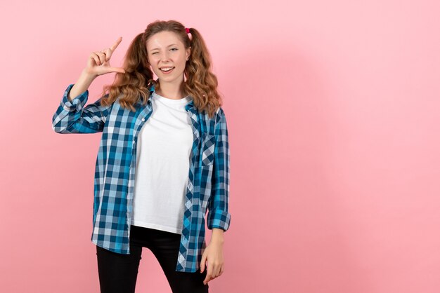 Vooraanzicht jonge vrouw in blauw geruit overhemd poseren op roze bureau emoties jeugd meisje model jongen mode