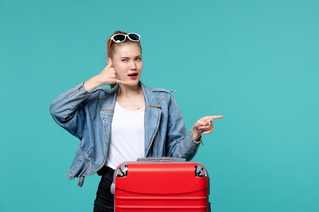 Vooraanzicht jonge vrouw in blauwe jas zich klaar voor reis poseren op blauwe ruimte