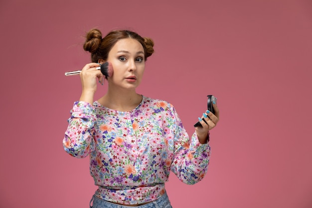 Gratis foto vooraanzicht jonge vrouw in bloem ontworpen shirt een make-up op de roze achtergrond