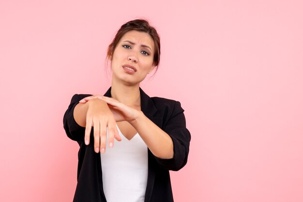 Vooraanzicht jonge vrouw in donker jasje met gekwetste arm op roze achtergrond