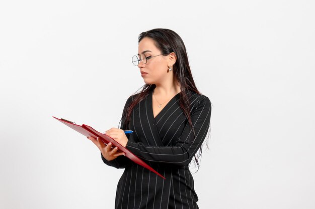 Vooraanzicht jonge vrouw in donker strikt pak met rood bestand op witte achtergrond kantoor zakelijke baan mode vrouwelijk document